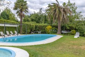 a swimming pool in a yard with two palm trees at Cabañita rústica con piscinas in Cambre