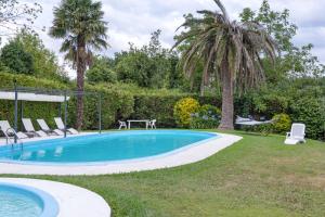a pool with chairs and a table and palm trees at Acogedor chalet rústico in Cambre