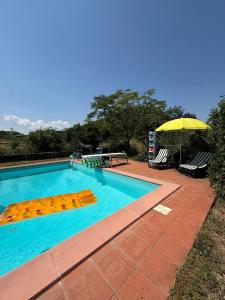 a swimming pool with a yellow umbrella and chairs at B&B la boffalora in Zaffignano