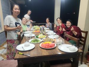 a group of people sitting around a table with food at Riva palace Homestay Rewalsar Lake in Malther