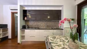 a kitchen with white cabinets and pink flowers in a vase at Crystal House in Montesilvano +18 photos