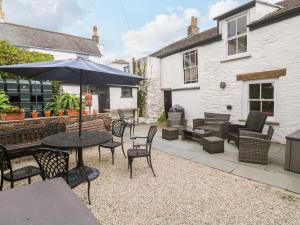 a patio with a table and chairs and an umbrella at 1 Dormer Villas in Porthscatho