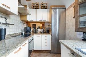 a kitchen with white cabinets and a stainless steel refrigerator at Acogedor chalet rústico in Cambre
