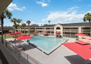 a swimming pool with red umbrellas in front of a building at Lyrios Vacation Rentals - Legacy in Kissimmee