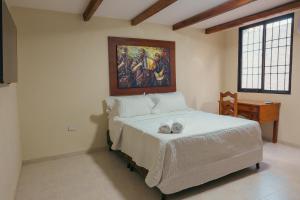 a bedroom with a bed with a painting on the wall at Hotel La Casona Del Valle in Valledupar