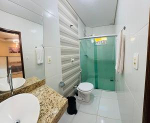 a bathroom with a toilet and a glass shower at Suíte Excellence - 01 in Pirenópolis