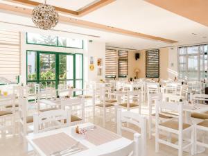 a dining room with white tables and white chairs at Oscar Hotel in Laganas