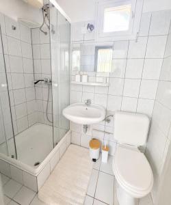 a white bathroom with a toilet and a sink at Nádaspart Vendégház in Zánka +3 photos