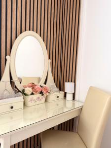 a dressing table with a mirror and pink roses at Sleep & Go Floreasca Green in Bucharest