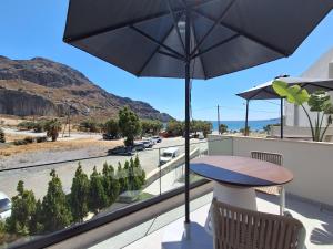 a balcony with a table and an umbrella at Paligremnos Infinity - Adults only in Plakias