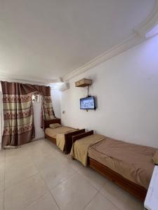 two beds in a room with a tv on the wall at Djerba Appartement in Houmt Souk