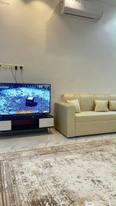 a living room with a couch and a flat screen tv at شقه ارضيه in Hail