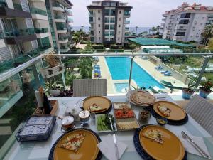 a table with plates of food on a balcony with a pool at WEDAT APART On the beach Moda Marine Residence in Alanya