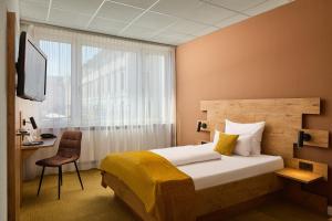 a bedroom with a bed and a desk and a window at Hotel Am Markt in Karlsruhe