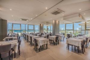 a dining room with tables and chairs and windows at AmbientHotels Panoramic in Rimini