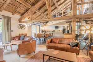 a large living room with leather furniture and a kitchen at Chalet de l'epigny in Bellecombe