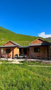 two wooden buildings with a green hill in the background at LEMI Mountain Cottages - Ushguli in Ushguli +27 photos