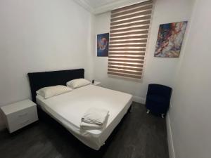 a bedroom with a white bed and a blue chair at Lafayette Apartment in Tunis