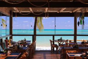 a restaurant with tables and chairs and a view of the ocean at Casa Manoa Pousada in Maragogi