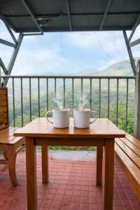 two coffee mugs sitting on a wooden table on a balcony at CloudHill Retreat in Ariankāvu