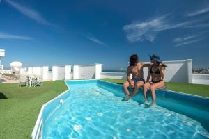 two women sitting on the edge of a swimming pool at AmbientHotels Panoramic in Rimini