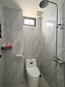 a bathroom with a white toilet and a shower at Nhan's Home in Hưng Nhơn (2)