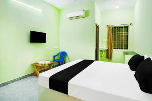 a bedroom with a bed and a chair and a television at Hotel O Royal Midlaans in Kālapettai