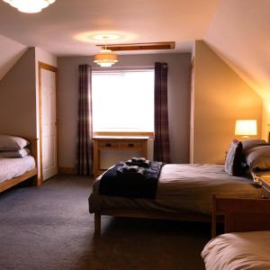 a bedroom with two beds and a window at Ardbrae Cottage in Daviot