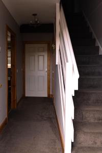 an empty hallway with a white door and stairs at Ardbrae Cottage in Daviot
