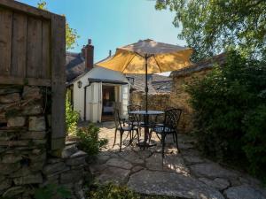 a table and chairs under an umbrella in a garden at Little Wickers in Wareham