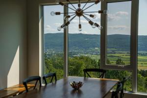 a dining room table with chairs and a large window at Luxury Coffee Bean Condo - Pool & Stunning View in Baie-Saint-Paul