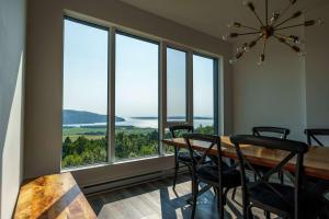 a dining room with a table and chairs and large windows at Luxury Coffee Bean Condo - Pool & Stunning View in Baie-Saint-Paul +49 photos