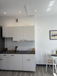 a white kitchen with white cabinets and a table at Willa Pod Platanem in Bytów
