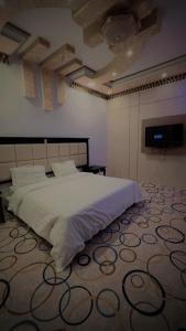 a bedroom with a large white bed with a carpet at السلطان هاوس in Najran