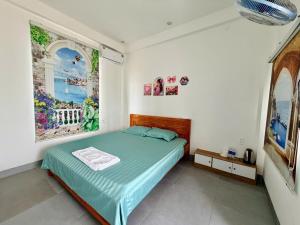 a bedroom with a bed with green sheets and pictures on the wall at Nhan's Home in Hưng Nhơn (2)