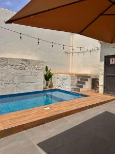 a swimming pool with a wooden deck and an umbrella at Casa Tulipán in Monterrey