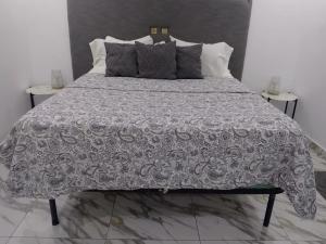 a bed with a gray and white comforter and pillows at Immobilier Du siecle in Abidjan