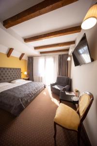 a bedroom with a bed and a chair and a tv at Bran Pensiunea Restaurant Al Gallo centru in Bran +90 photos