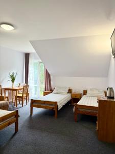 a room with two beds and a table and chairs at Pokoje Alina, 500m do morza ze śniadaniem in Grzybowo