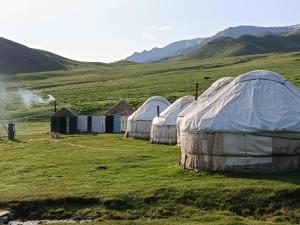 four tents in a field with mountains in the background at Bilalguesthouse in Dzhangyaryk