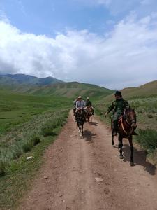 a group of people riding horses down a dirt road at Bilalguesthouse in Dzhangyaryk
