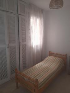 a bedroom with a bed and a window with shutters at Au Soleil le Vent in La Goulette