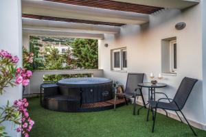 a patio with a hot tub and two chairs and a table at Βίλα Λαγονήσι in Kalívia Thorikoú
