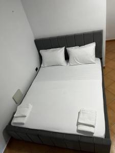 a bed with white sheets and pillows in a room at Hotel Gjakova-Shëngjin in Shëngjin