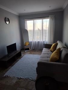 a living room with a couch and a large window at The Cottage Eplazini in Port Shepstone