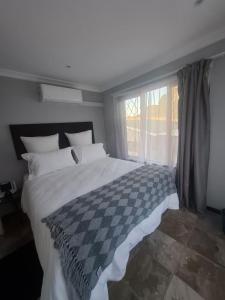 a bedroom with a checkered bed with a window at The Cottage Eplazini in Port Shepstone