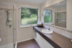 a bathroom with a sink and a shower and a mirror at Bliss by the Bay in Metung +10 photos