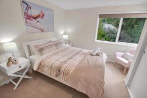 a white bedroom with a bed and a chair at Bliss by the Bay in Metung