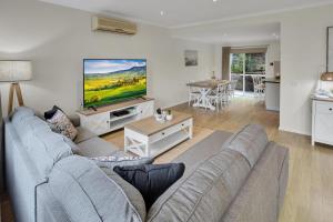 a living room with a couch and a flat screen tv at Bliss by the Bay in Metung