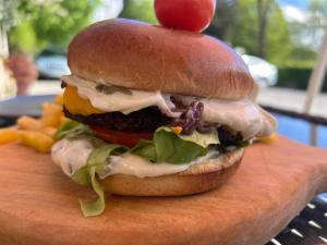 a hamburger with a tomato on top of it at Bran Pensiunea Restaurant Al Gallo centru in Bran